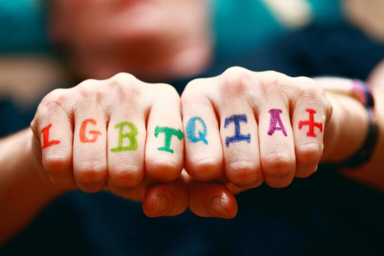 Vibrant hands displaying LGBTQIA+ pride symbols with rainbow colors.